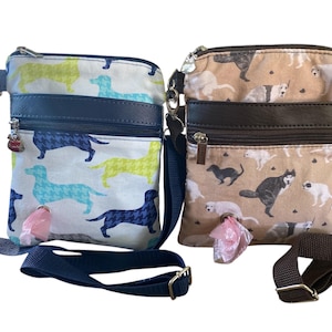 May include: Two crossbody bags with dog-themed prints and adjustable straps. The left bag is white with blue and lime green dachshund silhouettes. The right bag is tan with various dog illustrations. Both feature a front zipper and a waste bag dispenser.