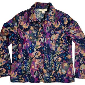 May include: A long-sleeved button-up jacket with a floral pattern in shades of pink, purple, blue, and yellow on a dark blue background. The jacket has a collar and two pockets.