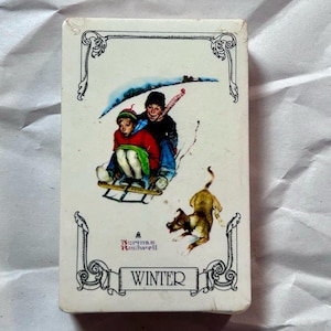 May include: A vintage card featuring a Norman Rockwell illustration of two children sledding down a snowy hill with a dog running behind them. The card is white with a black border and the word "WINTER" printed in black at the bottom.