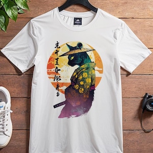 Könnte beinhalten: Weißes T-Shirt mit einer schwarzen Katze, die einen Samurai-Hut trägt und ein Schwert hält. Die Katze steht vor einem Sonnenuntergangs-Hintergrund mit japanischen Schriftzeichen.