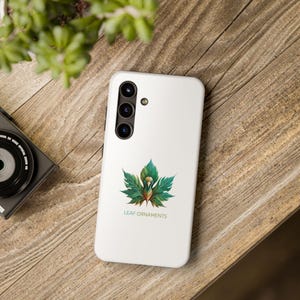 Może przedstawiać: Białe etui na telefon z zielonym i złotym wzorem liścia i tekstem "LEAF ORNAMENTS".