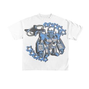 May include: White t-shirt featuring a blue and black graphic of a robot holding star-shaped objects. The robot has a detailed design with blue accents and a stern expression. The shirt is a casual style.