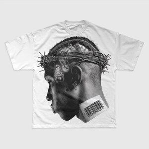 May include: White t-shirt with a black and white graphic of a person's profile wearing a barbed wire crown. A barcode is placed near the ear. The design is a detailed illustration.