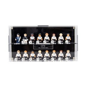 May include: A clear acrylic display case with a black background, showcasing a collection of 16 miniature soccer players in the German national team uniform. The case has two shelves and a label that reads "DFB - THE MANNSCHAFT".