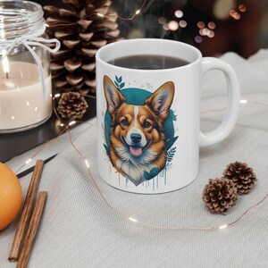 May include: White ceramic mug with a colorful illustration of a corgi dog with blue, green, and orange accents. The dog is looking directly at the viewer with its tongue sticking out.