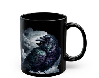 May include: Black ceramic mug featuring a detailed illustration of a raven with iridescent feathers against a backdrop of stormy clouds. The raven's feathers display shades of purple, green, and blue. The mug has a curved handle.