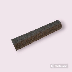 May include: Grey rolling pin with a repeating pattern of small skulls embossed on the surface.