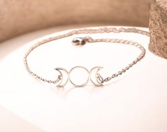 May include: A silver chain bracelet with a triple moon pendant charm. The chain is delicate and the pendant is simple and elegant.
