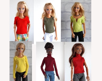 May include: A collection of doll outfits featuring various tops in red, olive green, and yellow. The tops include short-sleeved and long-sleeved styles, as well as a sleeveless tank top. The dolls are wearing the tops with different colored pants.