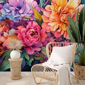 May include: A vibrant floral wallpaper featuring large, watercolor-style peonies in shades of pink, orange, and purple. A woven rattan chair with a white pillow and blanket sits in front of the floral backdrop, alongside a small side table and potted plants.