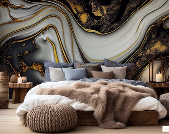 May include: A bedroom with a white, black and gold abstract wall mural. The bed has a white duvet and a brown faux fur throw. There is a brown knitted ottoman in front of the bed.
