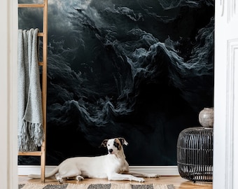 May include: A white dog with brown spots lies on a wooden floor in front of a dark blue and grey abstract wall mural. The dog is looking at the camera.