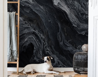 May include: A white dog with brown patches lies on a wooden floor in front of a black and white marbled wall. The dog is looking at the camera.