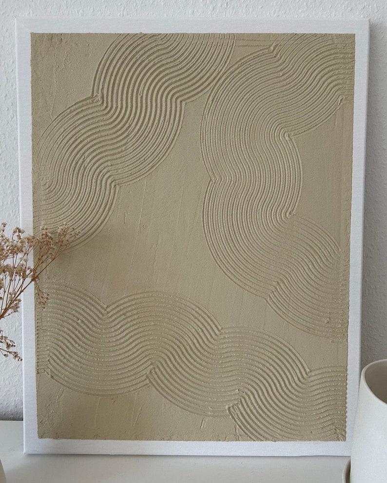 May include: A beige canvas painting with a textured, abstract design of overlapping curved lines.