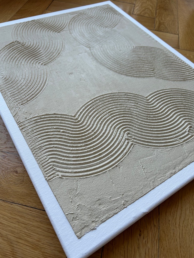 May include: A beige canvas painting with a textured surface. The painting features a pattern of curved lines in a light beige color.