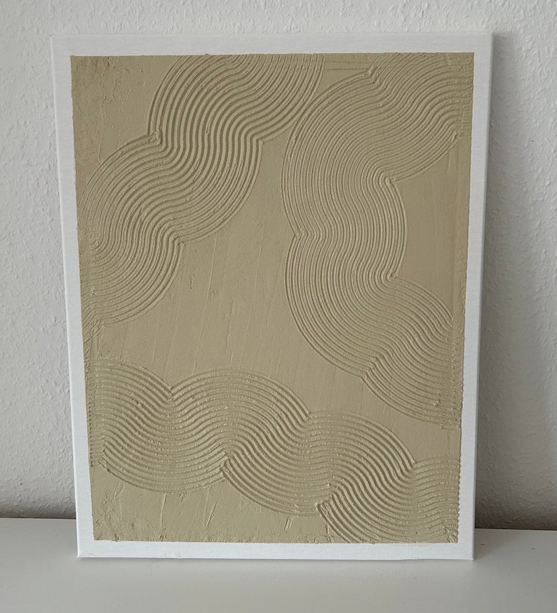 May include: A beige canvas painting with a textured, raised design of overlapping curved lines.