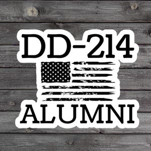 May include: A white sticker with the text "DD-214 ALUMNI" in bold, black letters. The design includes a distressed American flag in black and white, with stars and stripes. The sticker is on a wooden background.