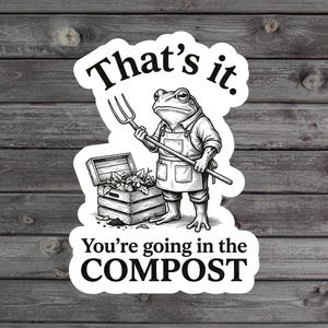 May include: A black and white sticker featuring a frog wearing an apron and holding a pitchfork next to a wooden crate filled with leafy greens. The text reads That's it. You're going in the COMPOST in bold black lettering on a white background.