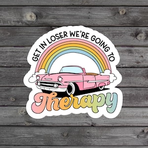 Pu&ograve; includere: Un adesivo con un'auto rosa vintage sotto un arcobaleno. Il testo "GET IN LOSER WE'RE GOING TO Therapy" &egrave; scritto sopra e sotto l'auto in un font retr&ograve;. L'adesivo ha un bordo bianco.