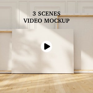 May include: Three white canvas frames with wooden frames, two are vertical and one is horizontal. The horizontal frame has a play button icon in the centre. The text "3 SCENES VIDEO MOCKUP" is above the frames.