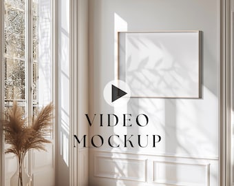 May include: A white wall with a large, rectangular, framed video mockup in the center. The frame is a light wood color. The video mockup is playing, indicated by a play button icon. The text "VIDEO MOCKUP" is below the frame.