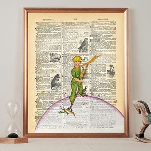 Könnte beinhalten: Eine Vintage-Wörterbuchseite mit einer handgezeichneten Illustration des kleinen Prinzen, der auf einem Planeten steht. Der Prinz trägt ein grünes und gelbes Outfit und hält einen Stock. Die Wörterbuchseite hat das Wort "Meridional" oben.