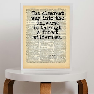 May include: A framed print featuring a vintage dictionary page background with the black text: The clearest way into the universe is through a forest wilderness. Below the quote, the text John Muir and John of the Mountains is visible.