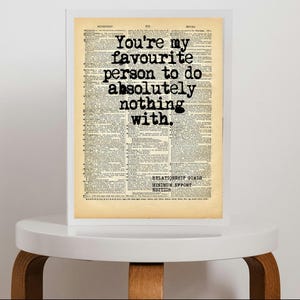 May include: A rectangular white frame containing a vintage dictionary page with aged beige paper. The black text reads: You're my favourite person to do absolutely nothing with. Below this, it says: RELATIONSHIP GOALS MINIMUM SUPPORT EDITION.