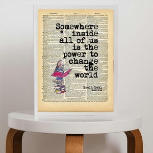 May include: A framed print with a vintage book page background. The print features the quote "Somewhere inside all of us is the power to change the world" in black text. A colorful illustration of a girl reading a book is also included. Signed by Ronald Dahl.