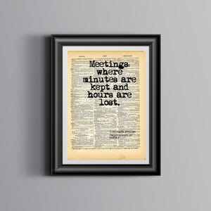 May include: A framed print featuring a vintage dictionary page with aged, yellowed paper. The black text reads: Meetings: where minutes are kept and hours are lost. Below this, smaller text reads: CORPORATE STUDIES PRODUCTIVITY IN THEORY.
