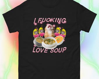 May include: Black t-shirt with a graphic of a cat and three cartoon cats holding hearts and bowls of soup. The text "I FUCKING LOVE SOUP" is printed in pink neon letters.