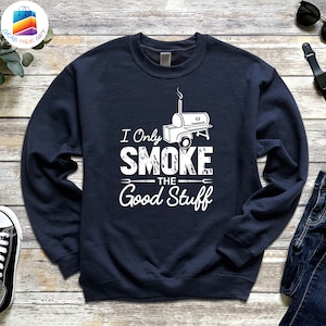 May include: Navy blue sweatshirt with white text that reads "I Only Smoke The Good Stuff" and a white illustration of a smoker.