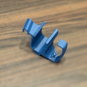 May include: A blue plastic phone holder with a small paper airplane logo and the text "Made of You" printed on it.