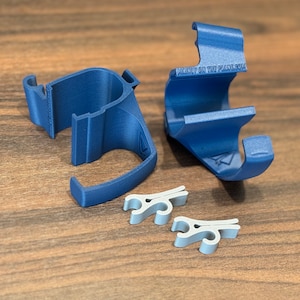 May include: Two blue 3D printed phone holders with the text "Mainly on the Planet 014" on one of the holders. Two silver clips are also included.