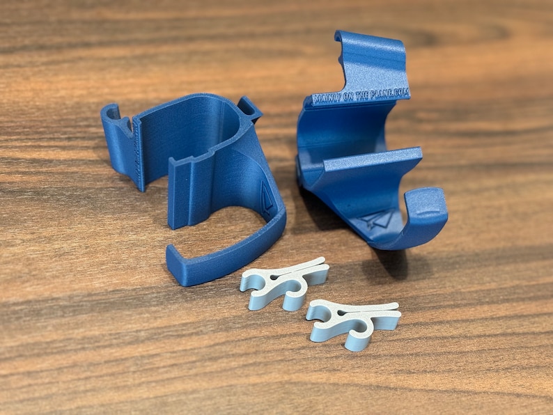 May include: Two blue 3D printed phone holders with the text "Mainly on the Planet 014" on one of the holders. Two silver clips are also included.