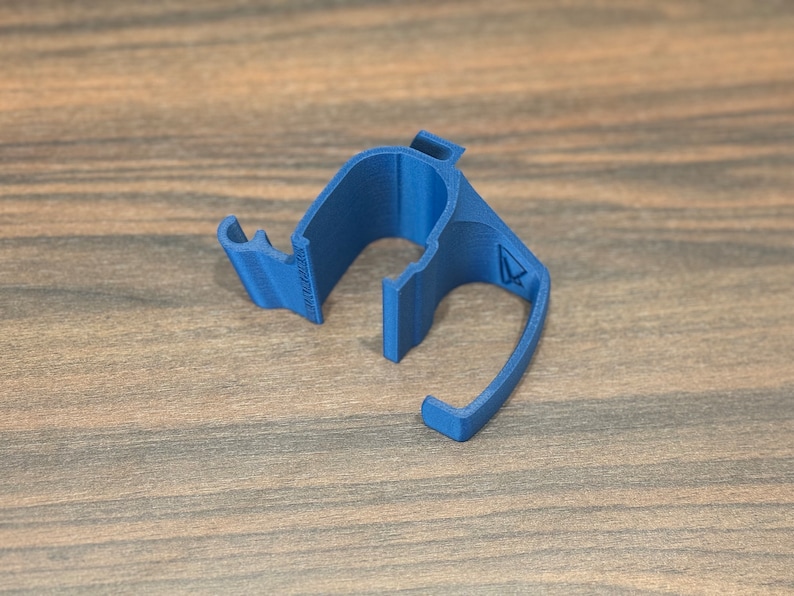 May include: A blue plastic cable clip with a small arrow on the side. The clip is designed to hold cables in place.