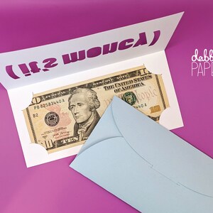 May include: A white card with a cut-out slot for money. The card has the text "(It2 WO&upsilon;&sigmaf;&lambda;)" printed in purple. A ten dollar bill is inserted into the slot. A light blue envelope is on the right side of the card.