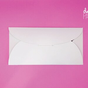 May include: A white envelope with rounded edges and a flap on the top. The envelope is on a pink background. The text "dabble PAPER" is printed in white on the top right corner of the image.