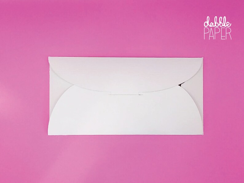 May include: A white envelope with rounded edges and a flap on the top. The envelope is on a pink background. The text "dabble PAPER" is printed in white on the top right corner of the image.