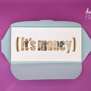 May include: A light blue card with a white interior. The interior has a cut-out design of the words "(it's money)" with dollar bills visible through the cut-outs.