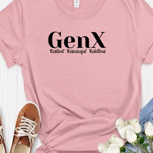 Puede incluir: Una camiseta rosa con el texto "GenX Resilient Resourceful Rebellious" impreso en negro.