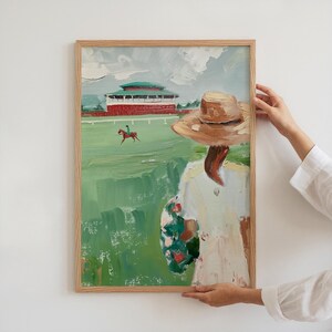 May include: A painting of a woman in a straw hat and white dress standing in a field, looking at a horse and rider in the distance. The woman is holding a bouquet of flowers. The painting is framed in a light wood frame.