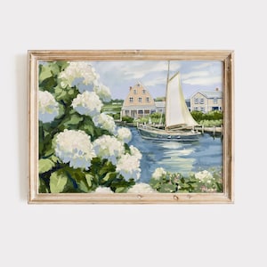 Könnte beinhalten: Gerahmtes Gemälde einer Küstenlandschaft mit einem Segelboot auf blauem Wasser. Weiße Hortensien blühen im Vordergrund, mit Häusern und einem bewölkten Himmel im Hintergrund. Der Rahmen ist helles Holz.