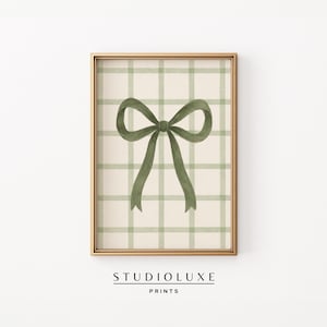 Puede incluir: Impresión enmarcada con un lazo de acuarela verde oliva sobre un fondo crema con un patrón de cuadros verdes. El marco dorado rodea la obra de arte. El texto "STUDIOLUXE PRINTS" se muestra en la parte inferior de la impresión.