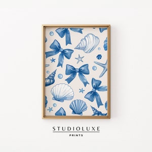 Può includere: Una stampa digitale con un motivo ripetitivo di fiocchi blu, conchiglie e stelle marine su uno sfondo crema. La stampa è incorniciata in una cornice dorata.