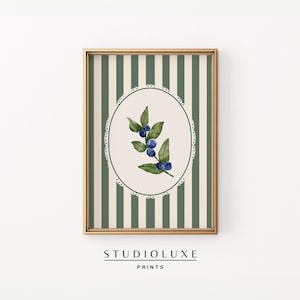 May include: A printable art print featuring a watercolor illustration of a green sprig with blue berries on a white background with a green and white striped border. The print is framed in a gold frame.