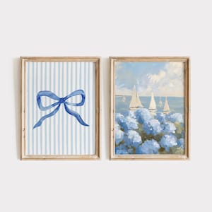 May include: Two framed prints, one with a blue bow on a white and blue striped background, and the other with a seascape of sailboats and blue flowers.
