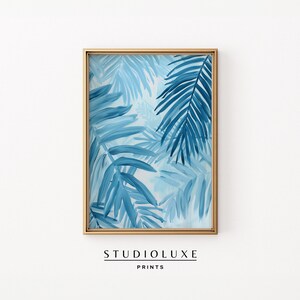 May include: A framed print of a blue and white abstract painting featuring palm leaves. The print is in a gold frame.