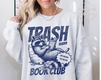 May include: A gray sweatshirt with a blue graphic of a raccoon reading a book. The graphic says "Trash Reader" and "The dirtier the better Book Club".