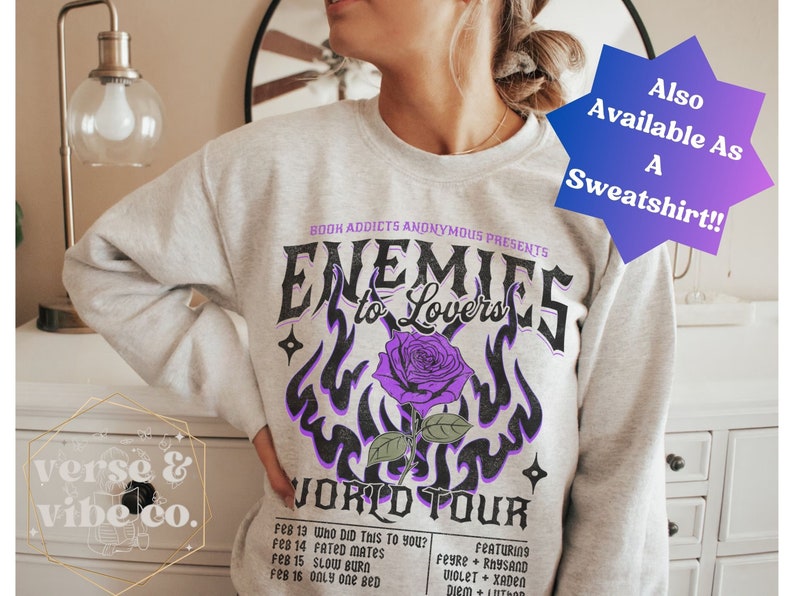 May include: Gray sweatshirt with a purple and black graphic design that says "Enemies to Lovers World Tour" with a purple rose and flames. The text "Book Addicts Anonymous Presents" is at the top of the graphic. The sweatshirt is available as a sweatshirt.